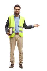 Bearded man holding books, wearing safety vest and gesturing welcome with hand