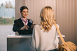 © LIGHTFIELD STUDIOS - smiling worker giving passport with boarding pass to young woman at check-in desk in airport