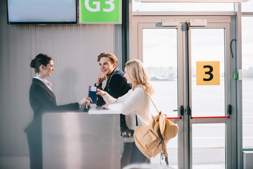 Wall Mural - side view of happy young couple at check-in desk in airport