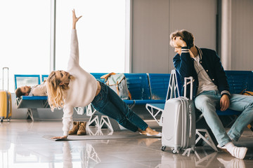 Wall Mural - beautiful girl practicing yoga while waiting flight in airport terminal