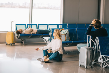 Wall Mural - young woman meditating in lotus position while waiting flight in airport terminal