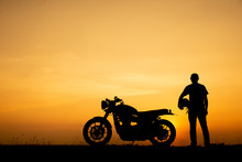 Silhouette Of Biker, Motorbike Parking With Sunset Background In Thailand. Young Traveller Man Standing And Holding Helmet Beside Motorcycle. Trip And Lifestyle Of Motorbike Concept
