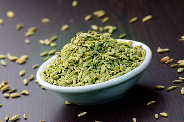 Wall Mural - Fennel seeds in a ceremic bowl on a wooden table