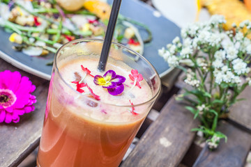 Fresh fruit juice on wooden table with flowers