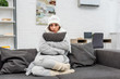© LIGHTFIELD STUDIOS - freezed young woman in warm clothes sitting on couch and hugging cushion at home