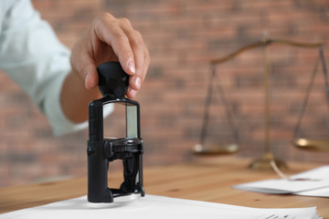 Wall Mural - Male notary stamping document at table, closeup. Space for text