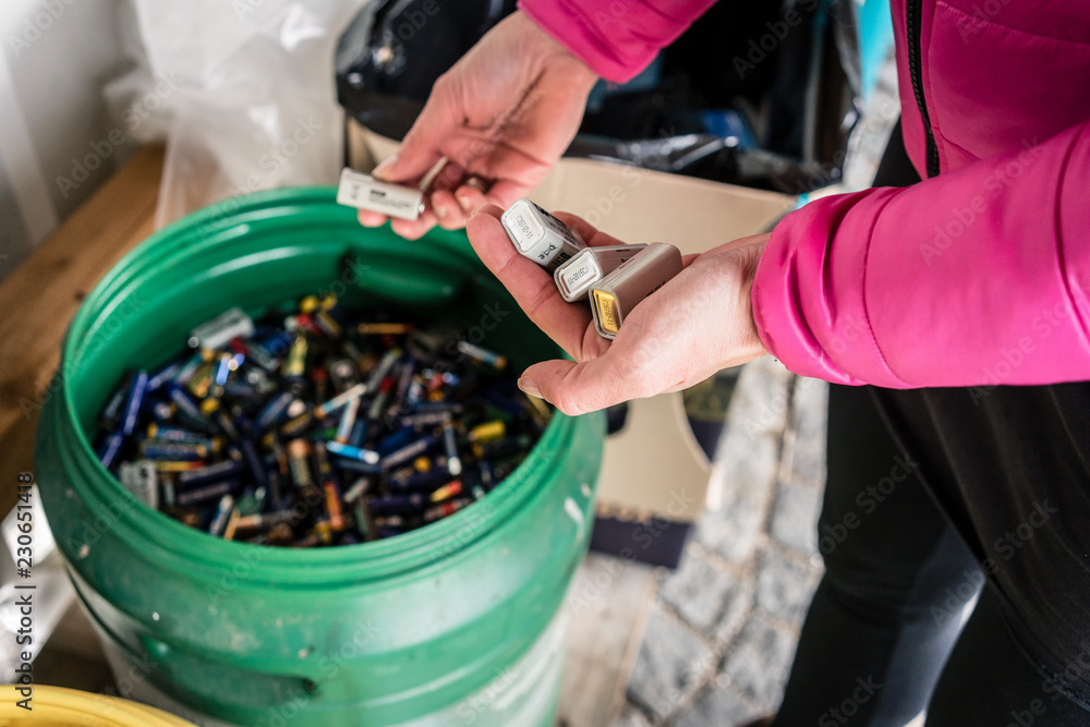 Batteries being disposed of in recycling center, hands of woman  - obrazy, fototapety, plakaty 