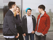 © Axel Bueckert - group of four young urban teenage friends talking laughing and having fun together - candid real people