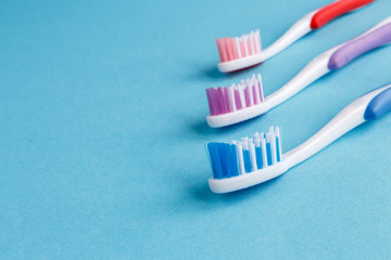 Wall Mural - concept of dental health. Three multicolored toothbrush and toothpaste on a blue background. Design, health care, healthy hygiene