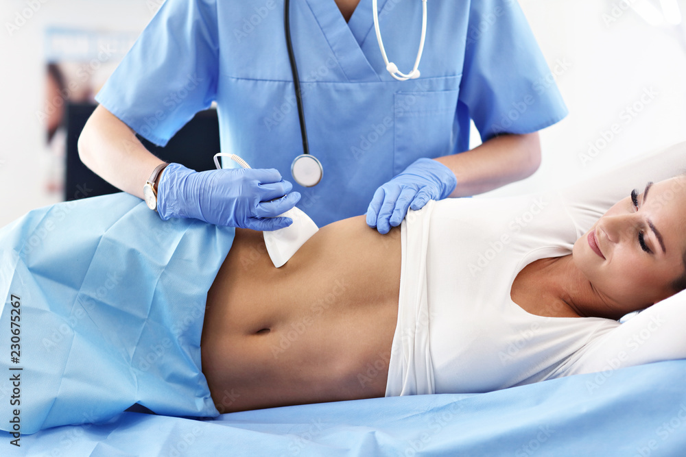Adult woman having abdomen ultrasound tests at female doctor's office - obrazy, fototapety, plakaty 