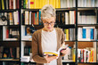 © dusanpetkovic1 - Focused young student girl standing in library in front of book shelf and looking at book. Searching for literature for her exam.