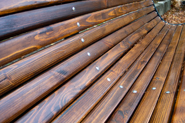 Angled view of a park bench with natural wood texture close up, shallow focus for use as autumn background