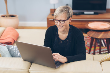 Happy smiling woman using a laptop at home