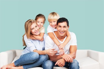 Canvas Print - Beautiful smiling family sitting at sofa at