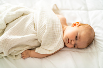 Wall Mural - A 4 month baby sleeping on a white bed at home