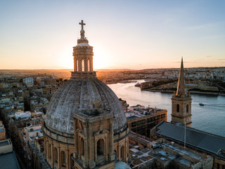 Aerial drone sunset photo over Our Lady of Mount Carmel basilica. A domed cathedral that overlooks the ancient capital city of Valletta, Malta. Island country in the Mediterranean Sea.