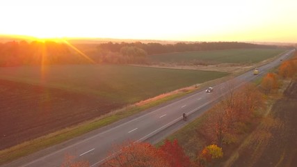 Wall Mural - Aerial: fly cam follow motorbike on the road at sunset time