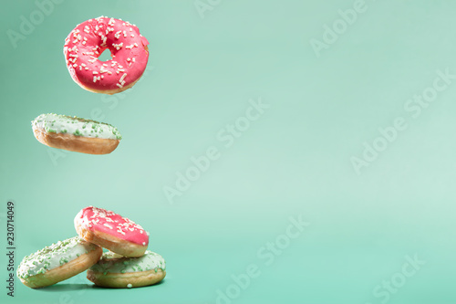 Cuadros en Lienzo Donuts with pink and green icing with sprinkles on mint backround with copyspace