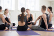 © fizkes - Group millennial people yoga lovers at sport seminar training studio. Sportive girls and guys young specialist colleagues learn more during workshop listen teacher coach communicate together indoors