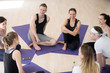 © fizkes - Millennial positive people sit together on mats in a circle during sport seminar girls guys listen teacher professional couch learn more about spiritual mental physical yoga practice, top above view