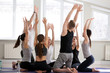 © fizkes - Group team of millennial guys and girls, wearing sportswear sitting in a circle on mats with hands raised having fun exercising together feels happy and healthy at yoga sport seminar in training