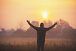 © vvvita - A happy man with hands in the air standing in the field in the early morning and looking at a sunrise