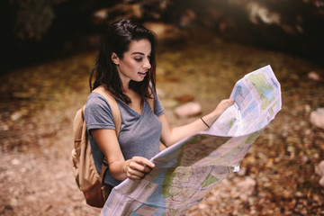 Wall Mural - Female hiker in forest reading a map