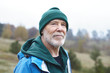 © shurkin_son - People, maturity age, retirement, nature, recreation and adventure concept. Portrait of handsome smiling senior male pensioner with thick gray beard, wrinkles and blue eyes walking outdoors