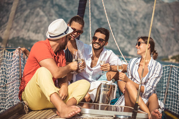 Wall Mural - Smiling friends sailing on yacht. Vacation, travel, sea, friendship and people concept