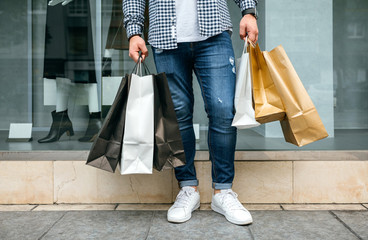 Low section of unrecognizable young man shopping with paper bags in his hand