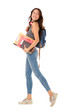 © mimagephotos - Full length smiling asian college student walking against isolated white background with books and bag