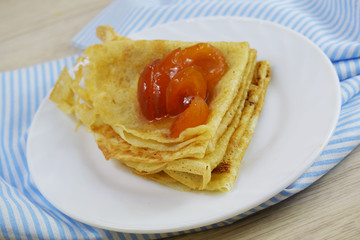 Wall Mural - Delicious hot pancakes with apricot jam on a white plate.