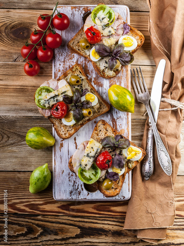 Fotografie, Obraz Three delicious sandwiches author's cuisine with poultry meat, avocado and tomatoes on a wooden background