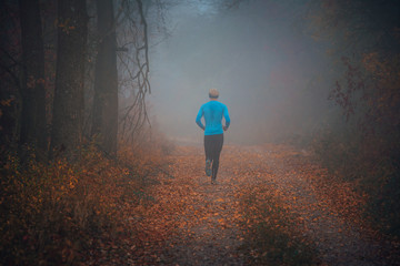 Wall Mural - Trail runner run in misty autumn forest