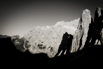 Black and white effect of shadows simulating two giants on dolomite walls of Cima Una and Cima Undici, South Tyrol, Italy