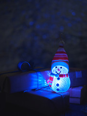 Snowman toy and gift in the dark at night on new year's eve