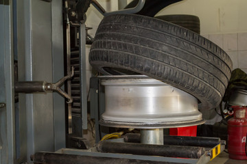 Canvas Print - Summer car tire half taken from the disk to perform tire mounting and fitting on a special machine in the workshop for repairing vehicles before the start of the winter season