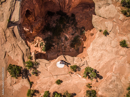 Fotografía Aerial drone photo - Bride and groom posing over a massive sinkhole in the Utah