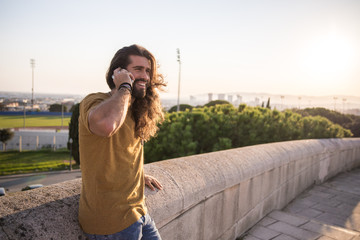 Wall Mural - young man with long hair using his mobile phone