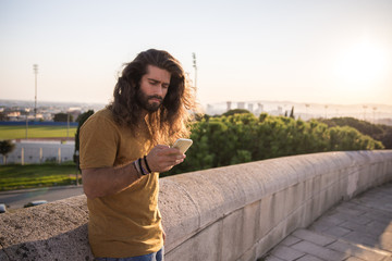 Wall Mural - young man with long hair using his mobile phone