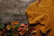 flat lay with fallen leaves and orange sweater on wooden tabletop