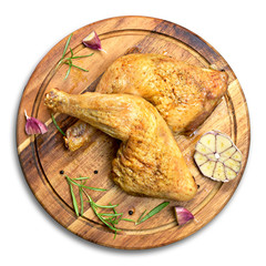 Delicious roast chicken legs or chicken drumsticks on a wooden cutting board. High angle view and fresh rosemary and garlic. Isolated on white background, top view.