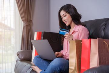 Sticker - happy woman using laptop computer for online shopping with credit card in living room