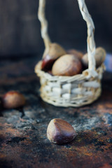 Canvas Print - Fresh chestnuts in basket over black rustic surface.