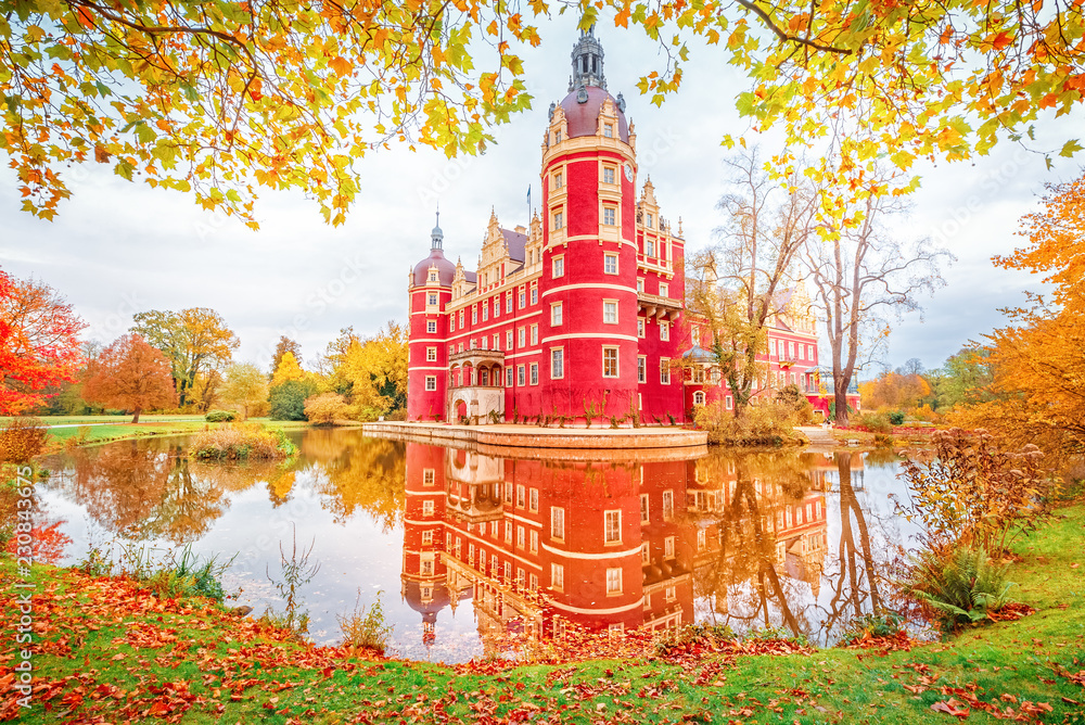 Bad Muskau Park and Palace - Famous UNESCO World Heritage site in Germany and Poland. Amazing Seasonal Autumn landscape with reflections of Great Classic architecture in Pond waters. Yellow leaves. - obrazy, fototapety, plakaty 