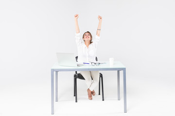 Celebrating businesswoman with laptop computer at office desk isolated on white background