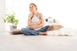 © amedeoemaja - home concepts, young woman hugging a big comfortable cushions, sitting on the wooden floor of a modern living room, copy space template