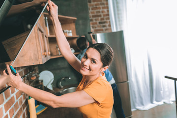 Take measures. Charming girl keeping smile on her face while measuring kitchen