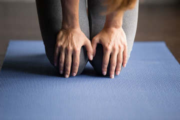 Wall Mural - Young sporty woman practicing yoga, doing knee strengthening exercise, healing physical therapy pose, working out, indoor close up, yoga studio