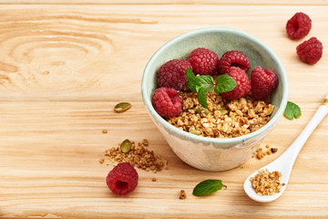 Wall Mural - Homemade granola in a bowl with raspberries on a wooden table.